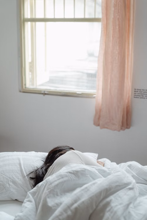 Person resting peacefully under soft blankets in comfortable bedroom